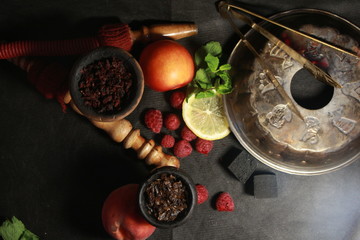 bowl with tobacco for hookah. fruits on a black background. smoke hookah