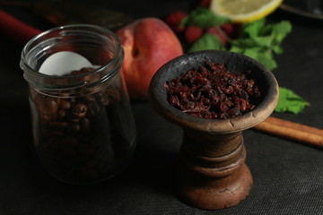 bowl with tobacco for hookah. fruits on a black background. smoking hookah