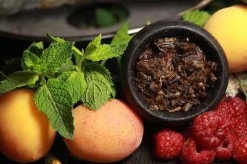 bowl with tobacco for hookah. fruits on a black background. smoke hookah