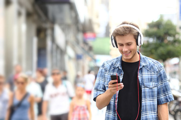 Happy boy walking listening to music in the street