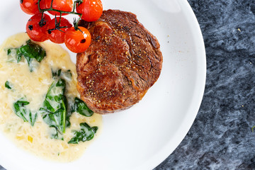 Close up view on restaurant served Medium Rare degree of Ribeye steak doneness with tomato and...