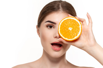 Close-up portrait of a happy beautiful young girl holding half of oranges close to face isolated over white background. Concept of beauty and health care.