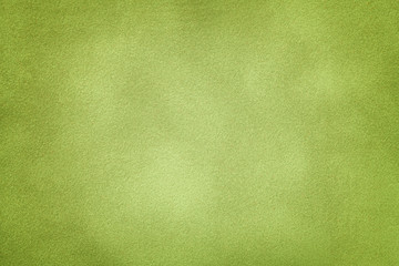 Background of light green suede fabric closeup. Velvet matt texture of olive nubuck textile