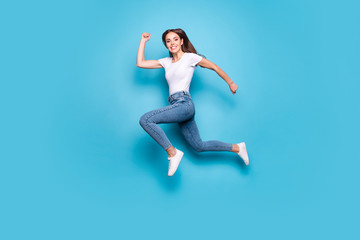 Fototapeta na wymiar Full body photo of charming sporty lady running training jogging wearing white t-shirt denim jeans isolated over blue background