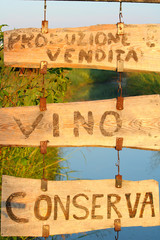 Italian wooden sign in the countryside, translation: "producing and selling wine, tomato sauce"