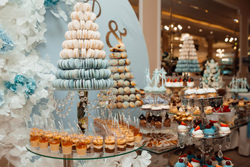 Candy bar with balls, macaroon, candy bar on holiday, candy bar at the wedding. Dessert table for a party. Cakes, cupcakes. Delicious sweets on candy buffet.  