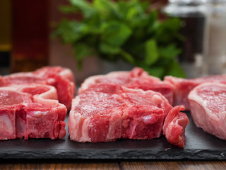 Fresh raw uncooked lamb chops in focus, Mint and pepper shaker out of focus.