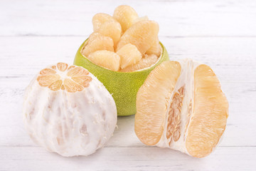 Fresh peeled pomelo, grapefruit, shaddock with green leaf on bright wooden plank table. Seasonal fruit near mid-autumn festival, close up, copy space