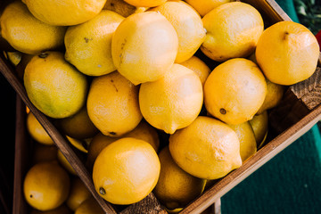 Harvest of lemons. Citrus yellow background. Lemons in box. Sour fruits for health. Hello, Autumn. Vegetarianism. Lemons top view. Place for an inscription. Copy space.