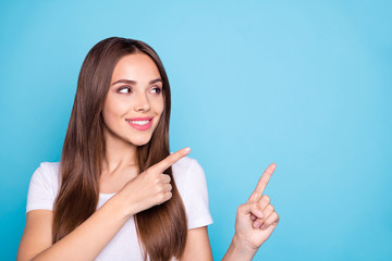 Close up photo of charming lady looking at copy space showing ads wearing white t-shirt isolated over blue background