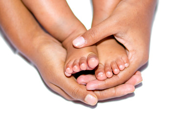 The soft legs of a baby placed on the palm of the mother's two hands on a white background.