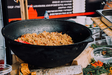 cauldron with pilaf. Uzbek cuisine. Food at festivals. Street food. Cooking in the fresh air. Large pan with food. Rice with meat and vegetables.