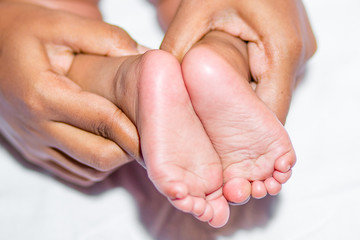 A mom holding baby’s two feet on a white background.
