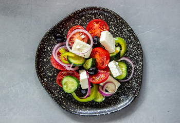 Greek salad on a concrete background. Tomatoes, peppers, olives, cheese, onions. Healthy eating. Diet. Vegetarian food.