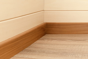 Corner of the room with walls, baseboards and natural wood floor