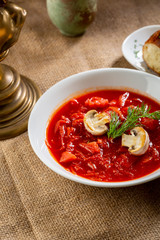 Red russian soup with mushrooms and bread in white bowl