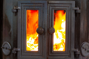 Close up old metal fireplace with doors and fire