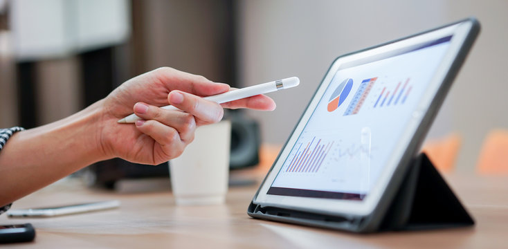 Close Up Salesman Employee Hand Using Stylus Pen To Pointing On Tablet Screen To Show Company Profit Monthly In The Meeting Event At Conference Room , Business Strategy Concept