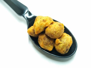 A picture of salty peanuts on a black spoon