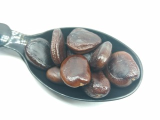 A picture of tamarind seeds on a black spoon