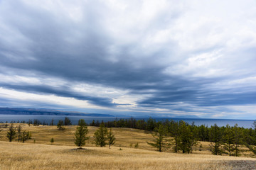 Fototapeta na wymiar Lake Baikal, tree and mountains of Siberia with beautiful sky and clouds, Russia Oklhon island