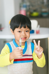 A sick Asian boy eating medicine from a plastic syringe by himself. 