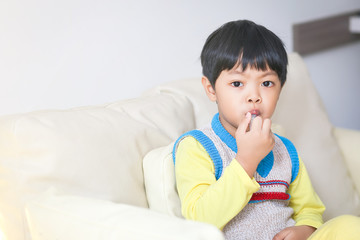 A sick Asian boy eating medicine from a plastic syringe by himself. 