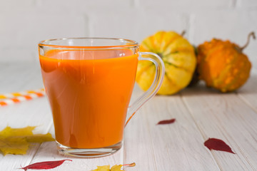 Glass of fresh pumpkin smoothie on white wooden background