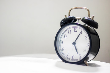 Antique black clock on the table with white linen