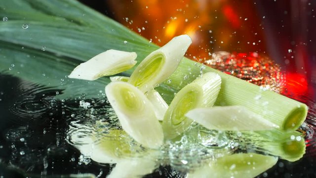 Green stems of leek slices falling into the water table in SLOW MOTION , 4k