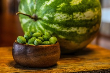 Large Fresh Watermelon on Wooden Board next to Mexican Sour Gherkins in bowl, selective focus