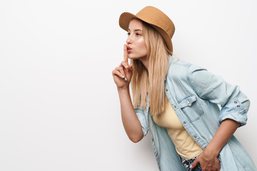 Serious amazing young pretty woman wearing hat posing isolated over white wall background showing silence gesture.