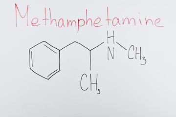 top view of white board with chemical formula and lettering methamphetamine