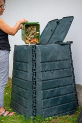 female emptying a bucketful of kitchen waste to the compost bin