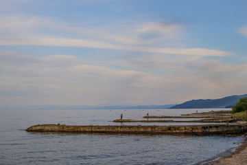 Fototapeta na wymiar Lake Baikal. On breakwaters, fishermen catch fish with fishing rods.