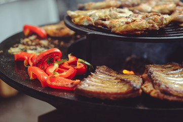 The chef is cooking meat on the grill. Golden rib steaks and chicken with grilled vegetables, delicious food