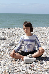 Fototapeta na wymiar eyes closed child relaxing for yoga and mindfulness on pebbles