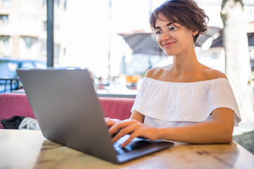 Smiling woman in cafe using laptop outdoors