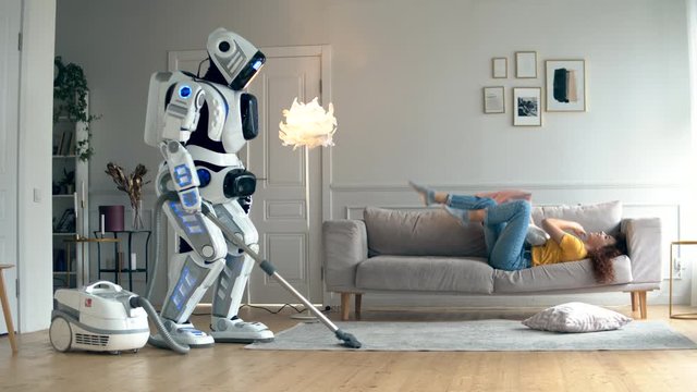 White cyborg is vacuum cleaning while a girl is having fun.