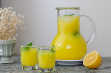Glasses of lemonade with sliced lemon on wooden background.