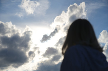Woman look at cloudy sky, cumulus clouds lights in sun rays