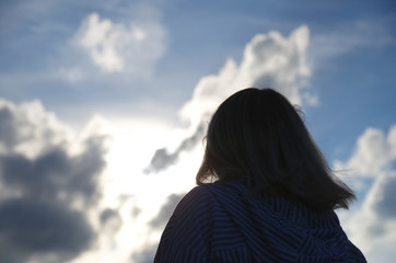 Woman look at cloudy sky, cumulus clouds lights in sun rays