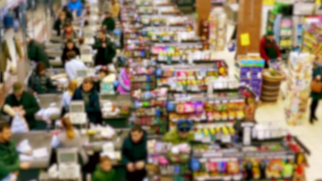 Cashier at supermarket / Retail checkout / Paying groceries. Unrecognizable buyers with carts move in queues to pay for purchases at the supermarket cashier. Slow motion.
