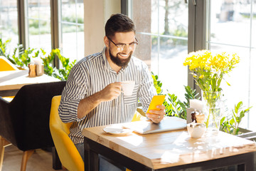 Cheerful nice man sitting with his smartphone