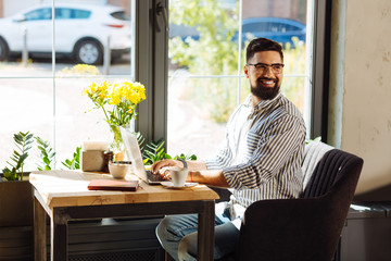 Joyful nice man working from the cafe