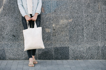 Woman holding white textile eco bag against urban city background. . Ecology or environment...