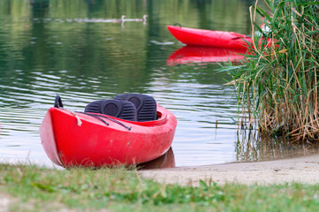 Red kayak by the shore of a river. Selective focus.