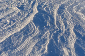 Snow on a frozen lake blown by wind creating a pattern.