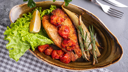 Baked salmon fillet with tomatoes and stern celery on a plate. Diet and healthy food concept. Top view