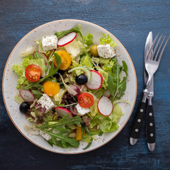 Healthy salad with fresh vegetables, lettuce, arugula and cheese. Top view.